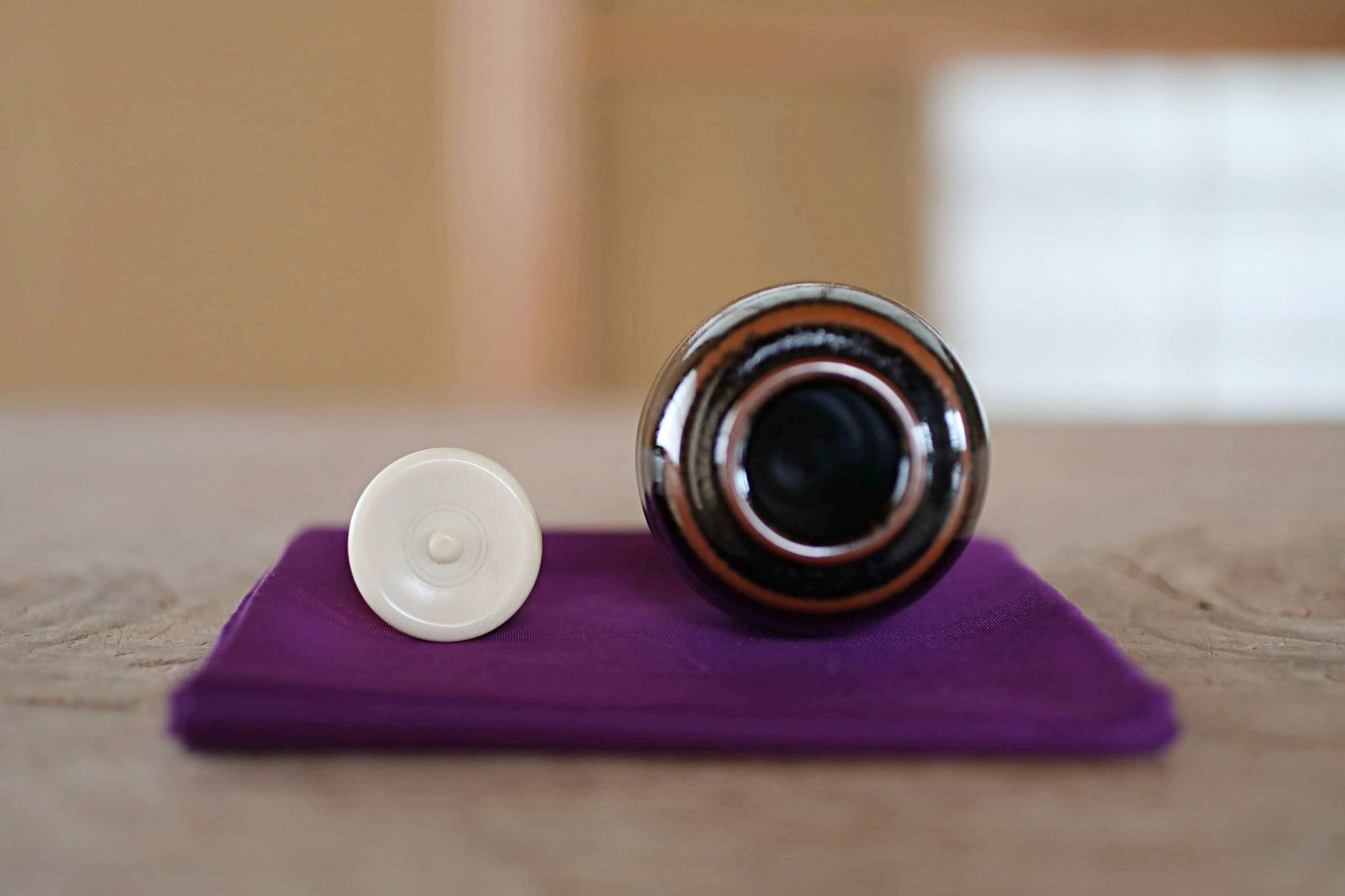 a black and brown bottle with a white cap, placed on a purple cloth on a wooden surface.