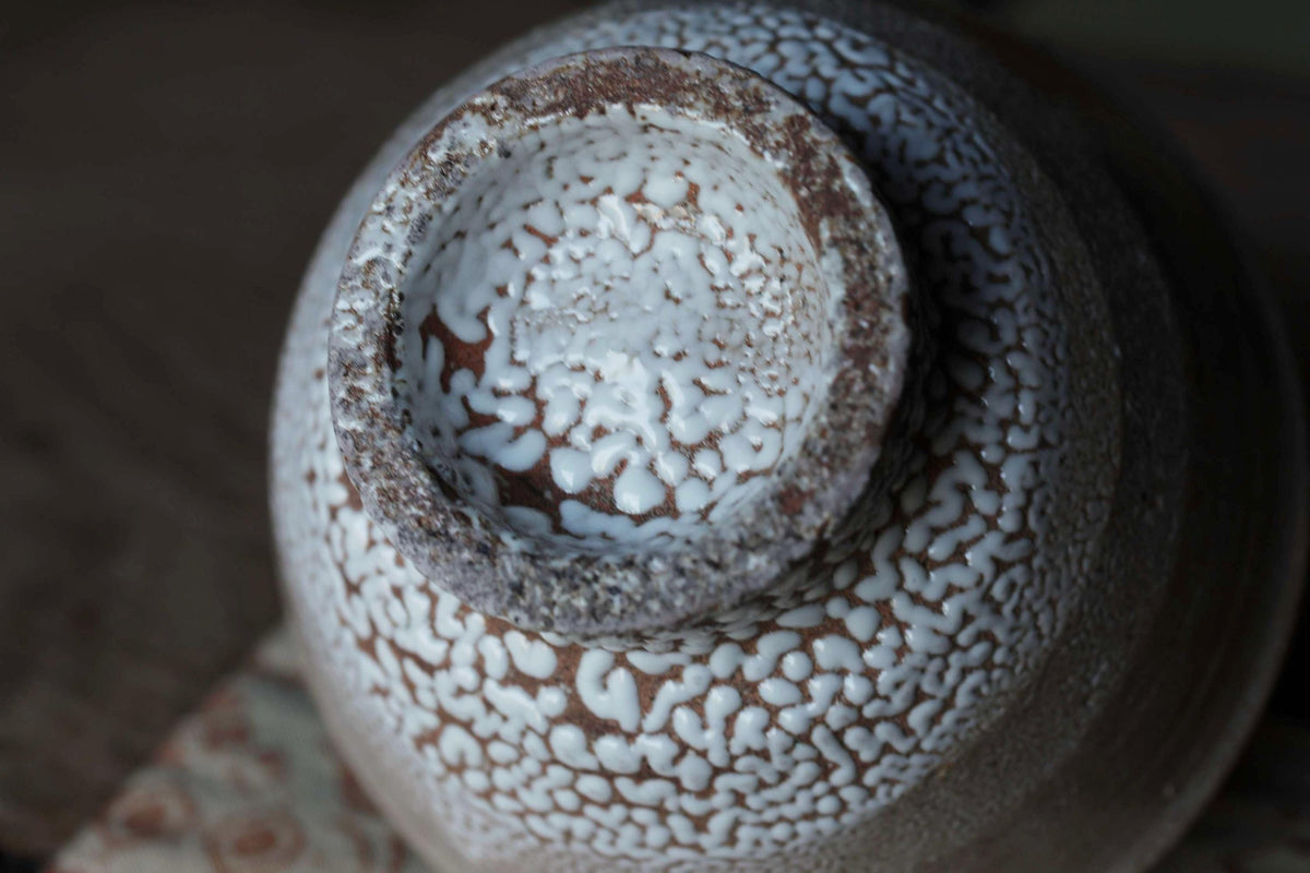 A close-up image of a ceramic bowl with a textured, speckled surface.
