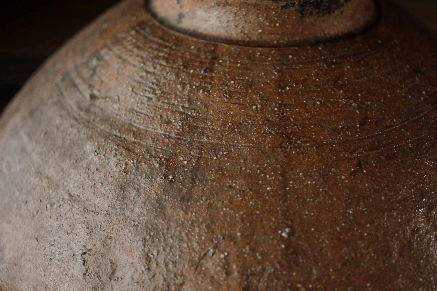 A close-up image of a weathered, brown ceramic object with visible cracks and stains, suggesting it has been used for an extended period of time.