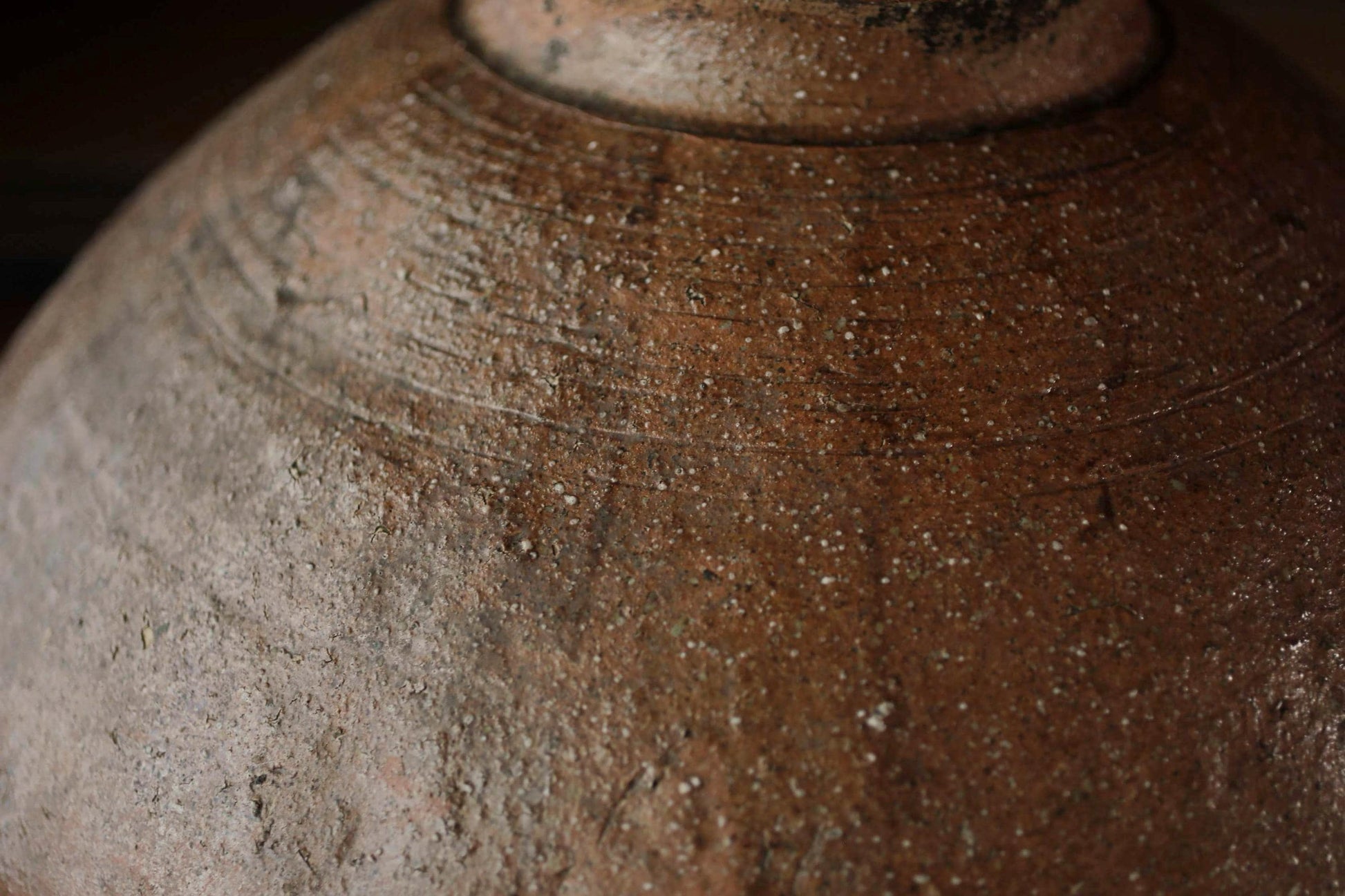 A close-up image of a weathered, brown ceramic object with visible cracks and stains, suggesting it has been used for an extended period of time.