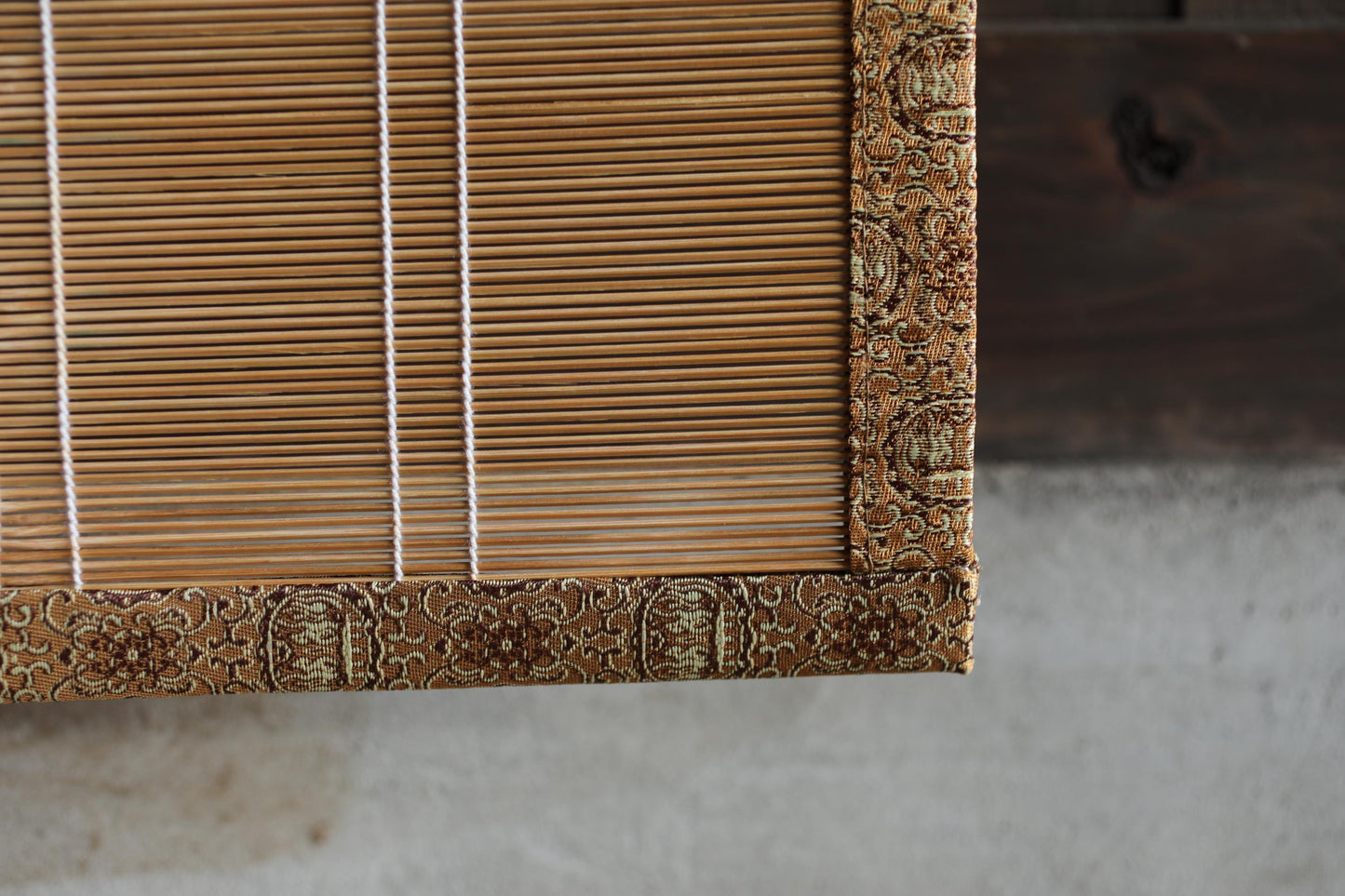 a close-up view of a wooden blind with a decorative border, featuring vertical slats and a patterned edge.