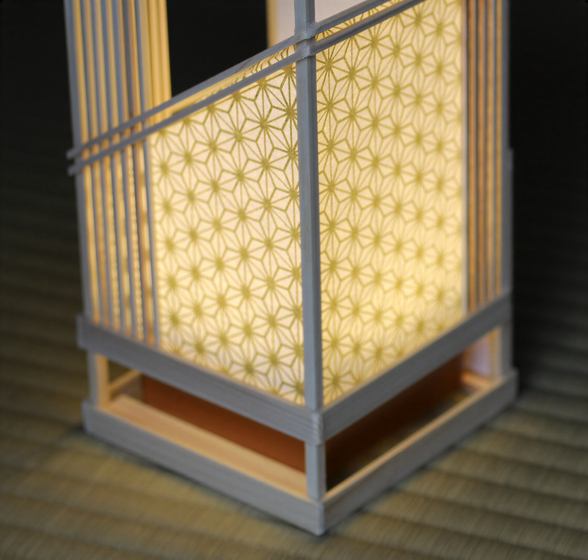 A close-up view of a decorative lamp with a geometric patterned design, illuminated and casting a warm glow.