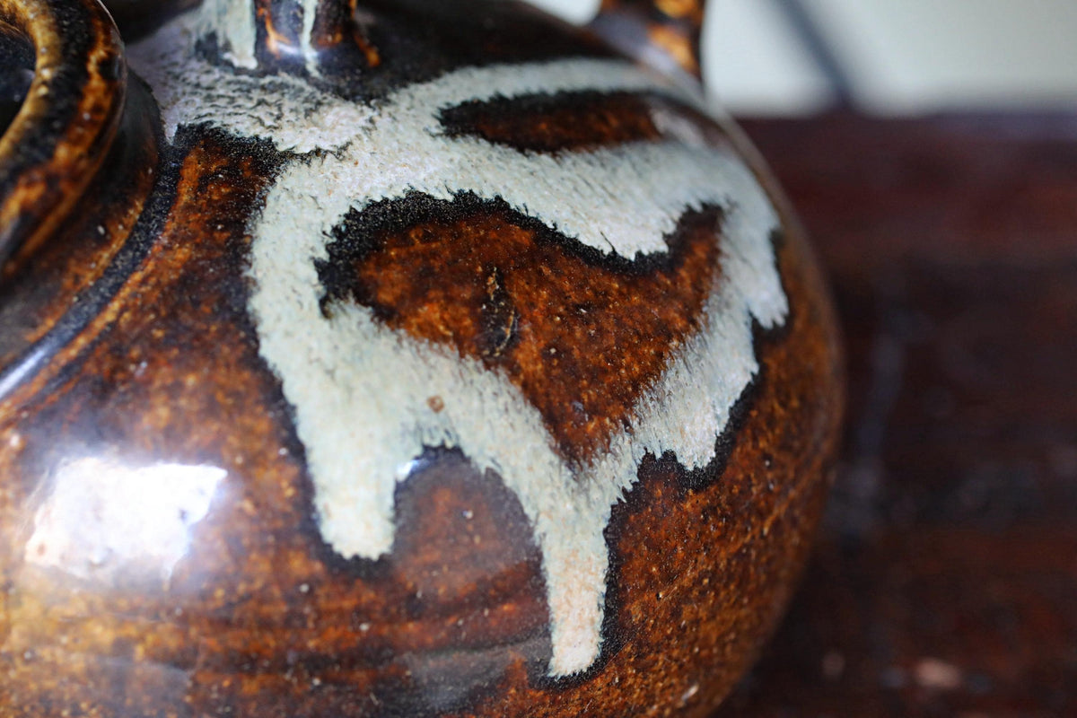 A close-up image of a brown and white ceramic vase with a distinctive design on its surface.