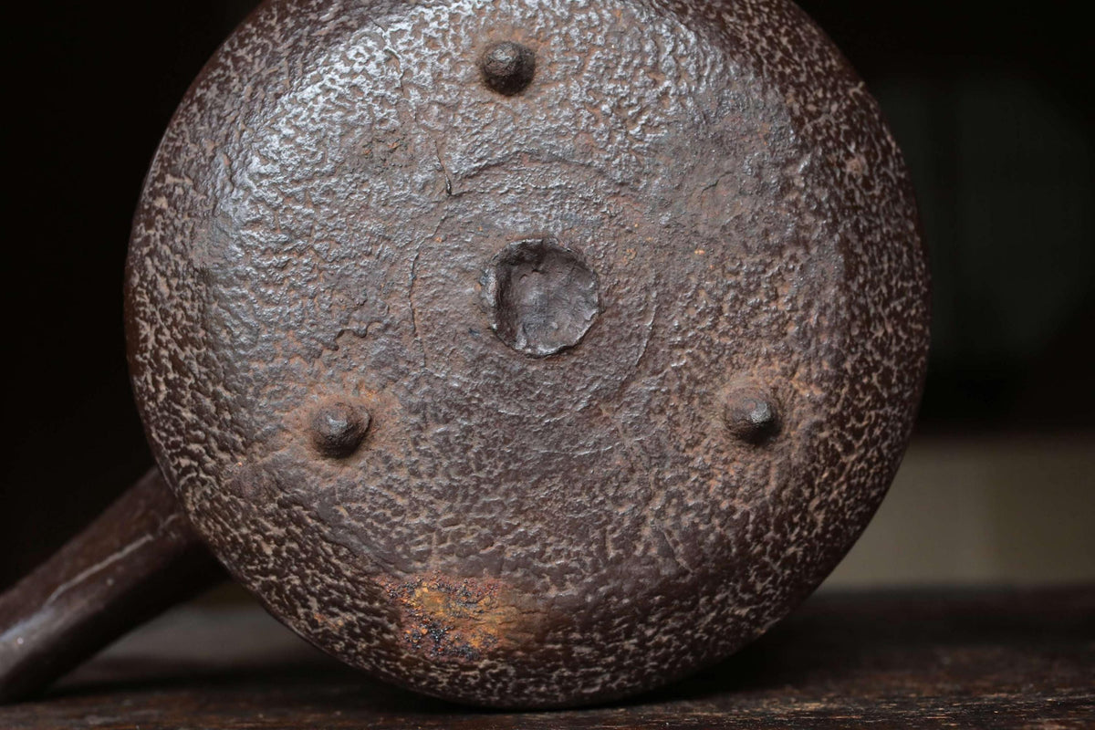 a close-up view of a rusted metal object, possibly a piece of machinery or a tool, with a textured surface and three small holes or rivets.
