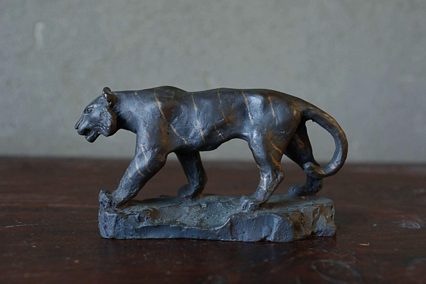 A bronze sculpture of a panther is displayed on a wooden surface.