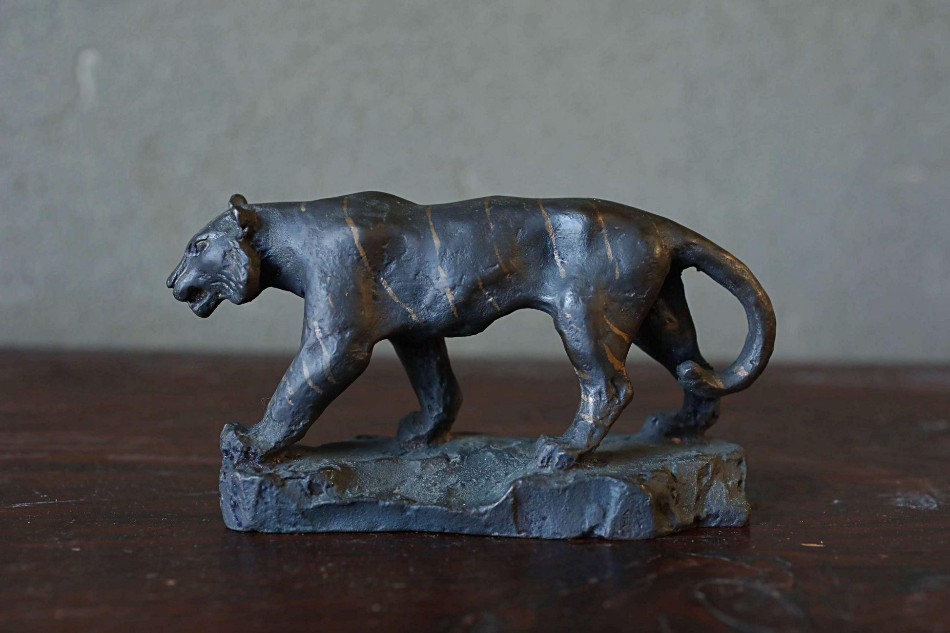 A bronze sculpture of a panther is displayed on a wooden surface.