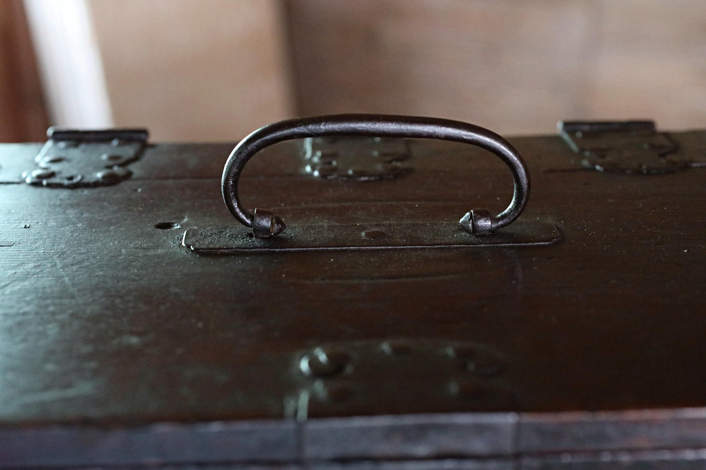 a close-up view of a metal handle on a dark wooden surface.