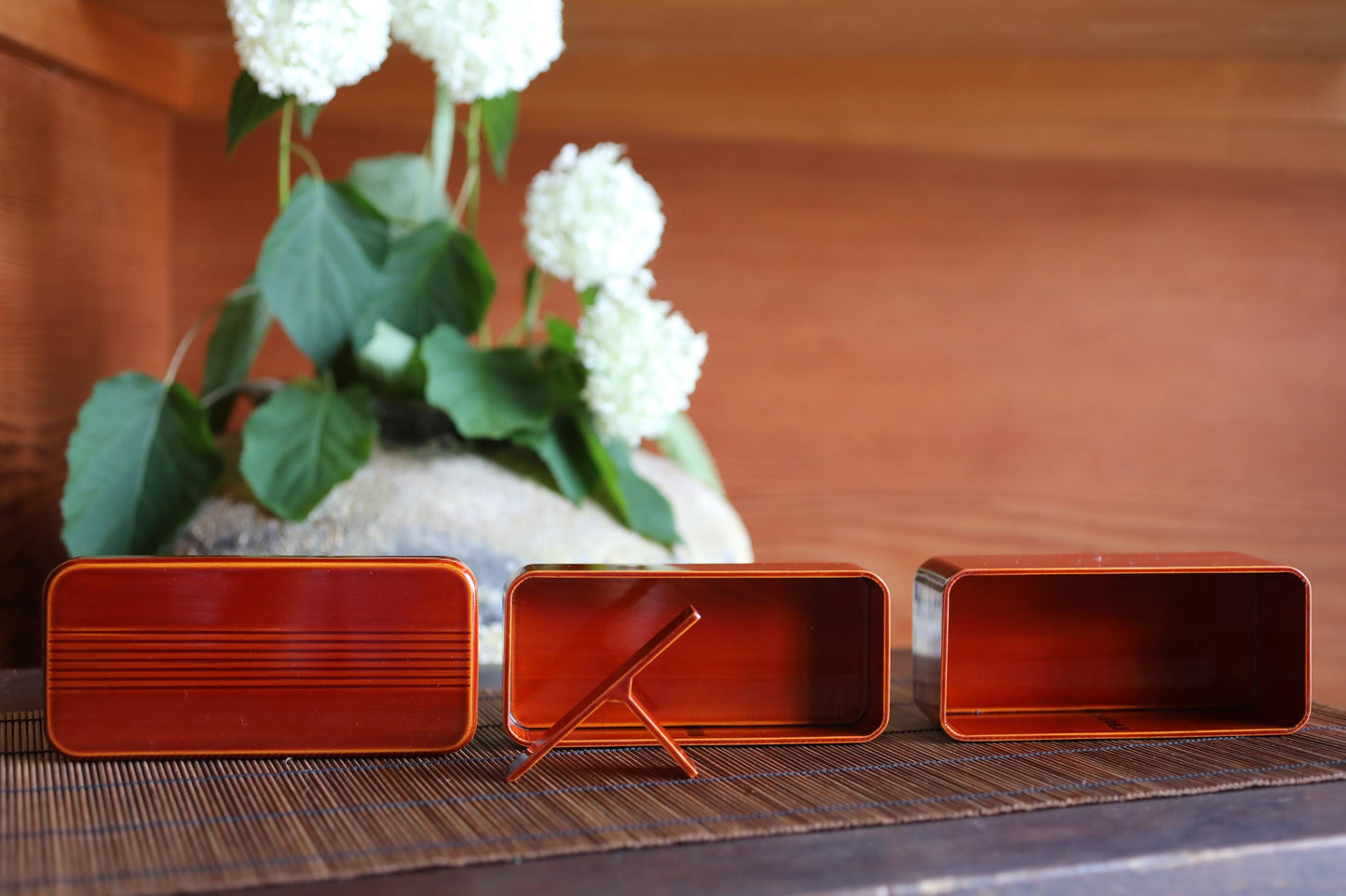 three red metal containers with a plant in the background.