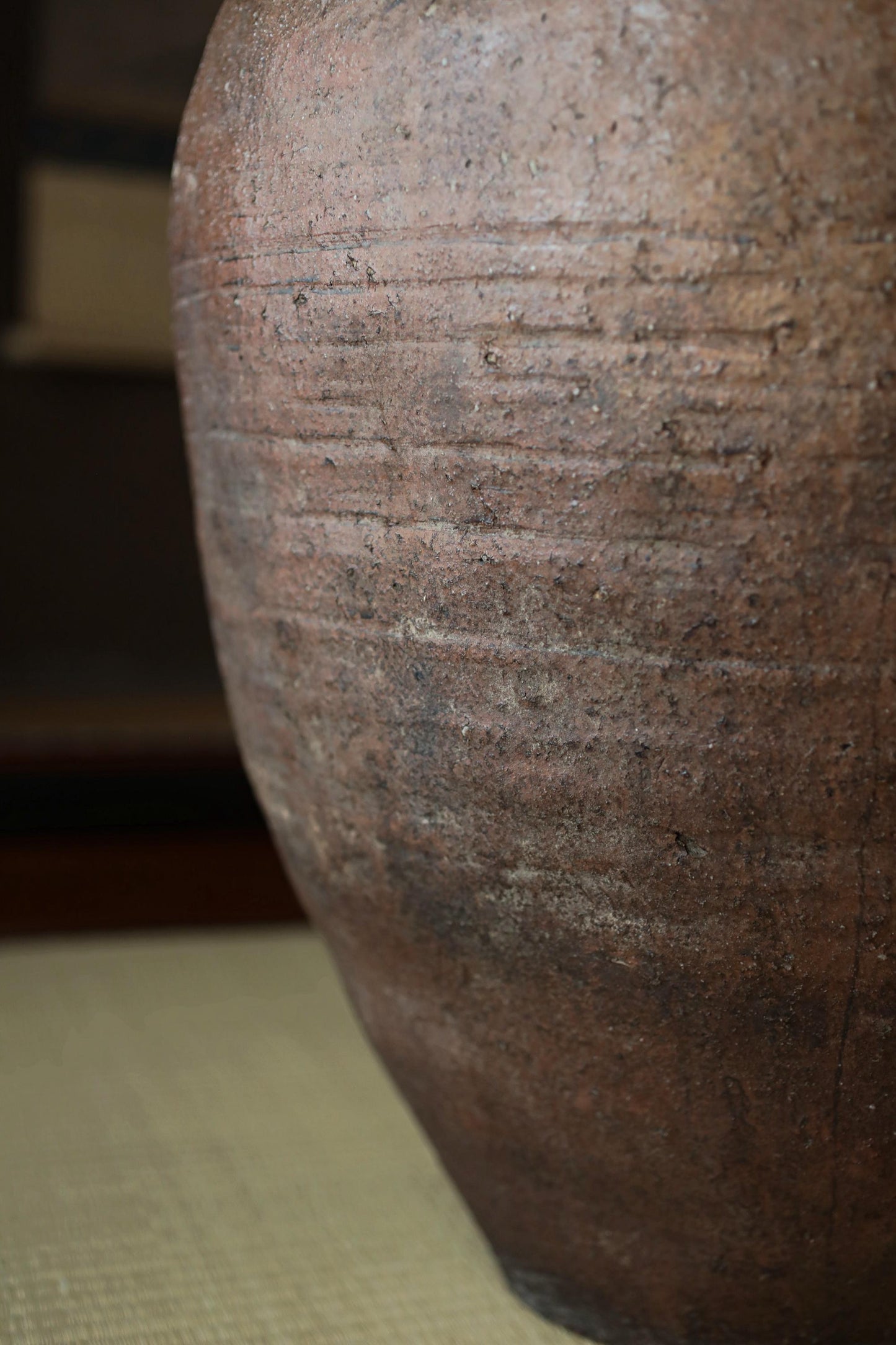 A close-up view of a large, brown, textured vase or urn with a rough, weathered appearance.