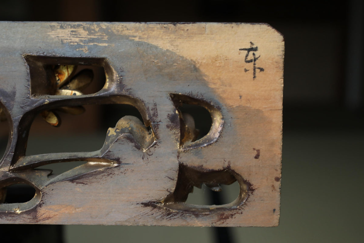 a close-up view of a wooden surface with a carved design, featuring a symbol or text that is not clearly visible.