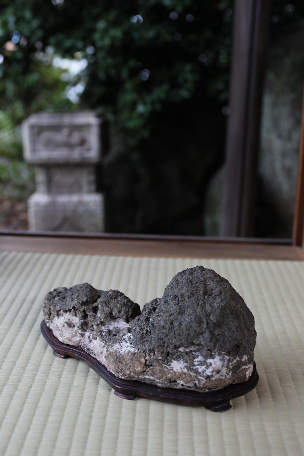a large, dark-colored rock or stone on a wooden stand, placed on a woven mat or mat-like surface.