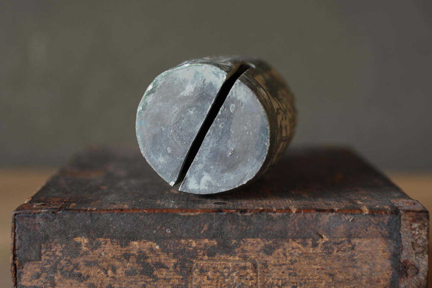 A metal object with a circular shape, possibly a tool or piece of machinery, is resting on a wooden surface.