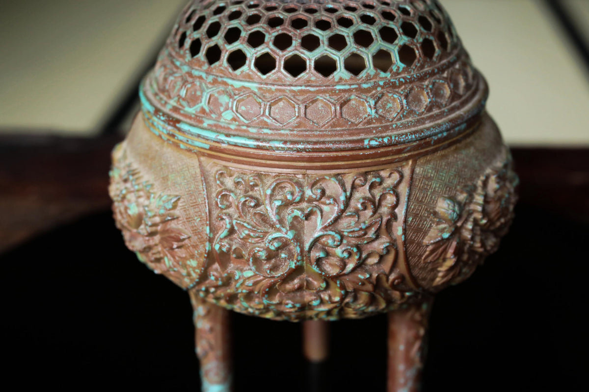 An ornate, antique-looking metal incense burner with intricate designs and patterns.