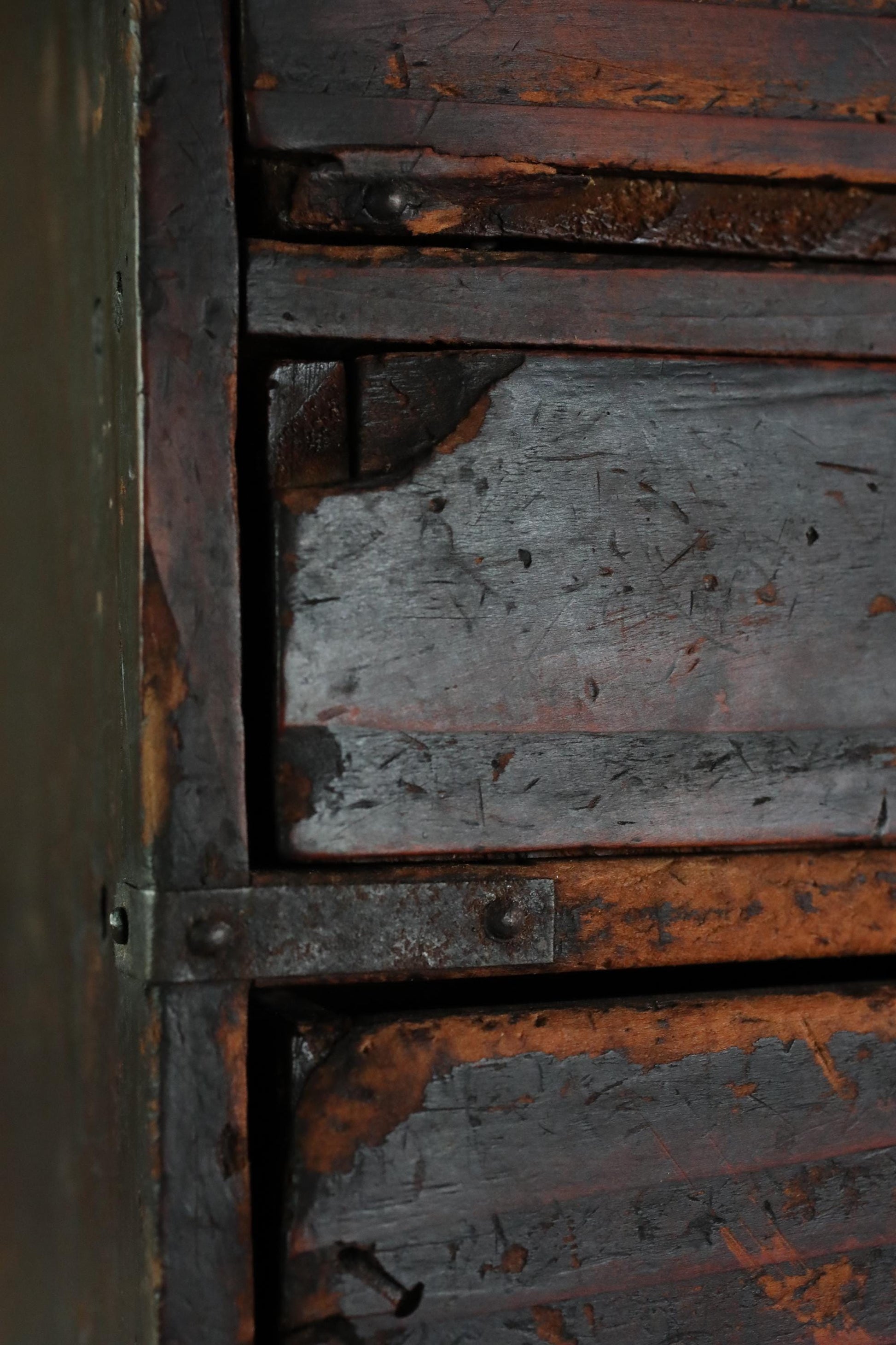 a close-up view of a weathered, wooden surface with visible signs of rust and peeling paint.