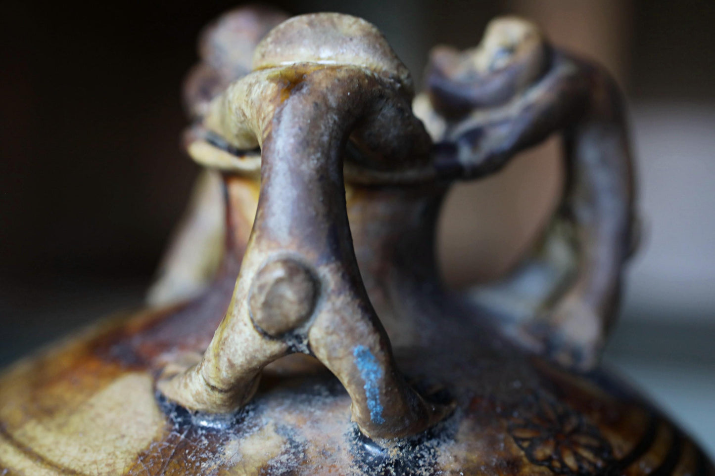 A close-up view of a ceramic vase or container with a unique, abstract design featuring a combination of shapes and textures.