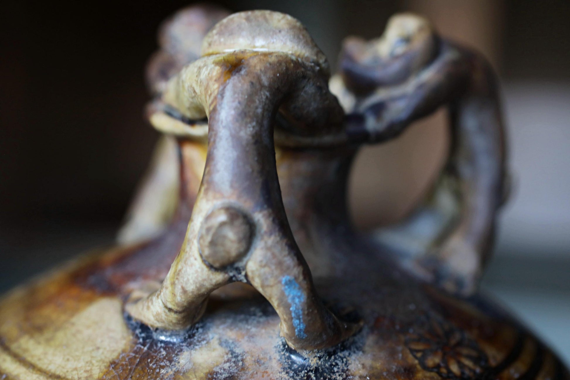 A close-up view of a ceramic vase or container with a unique, abstract design featuring a combination of shapes and textures.