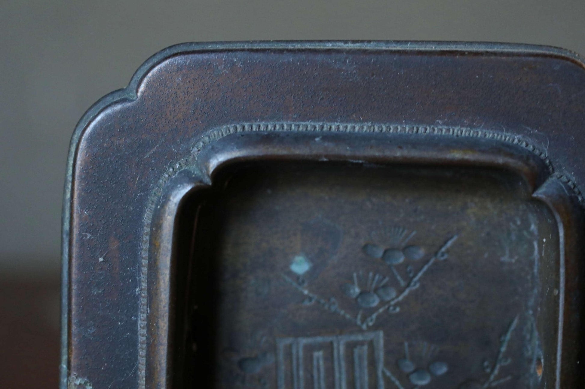 a close-up view of a dark metal object, possibly a piece of furniture or a decorative item, with a detailed design on its surface.