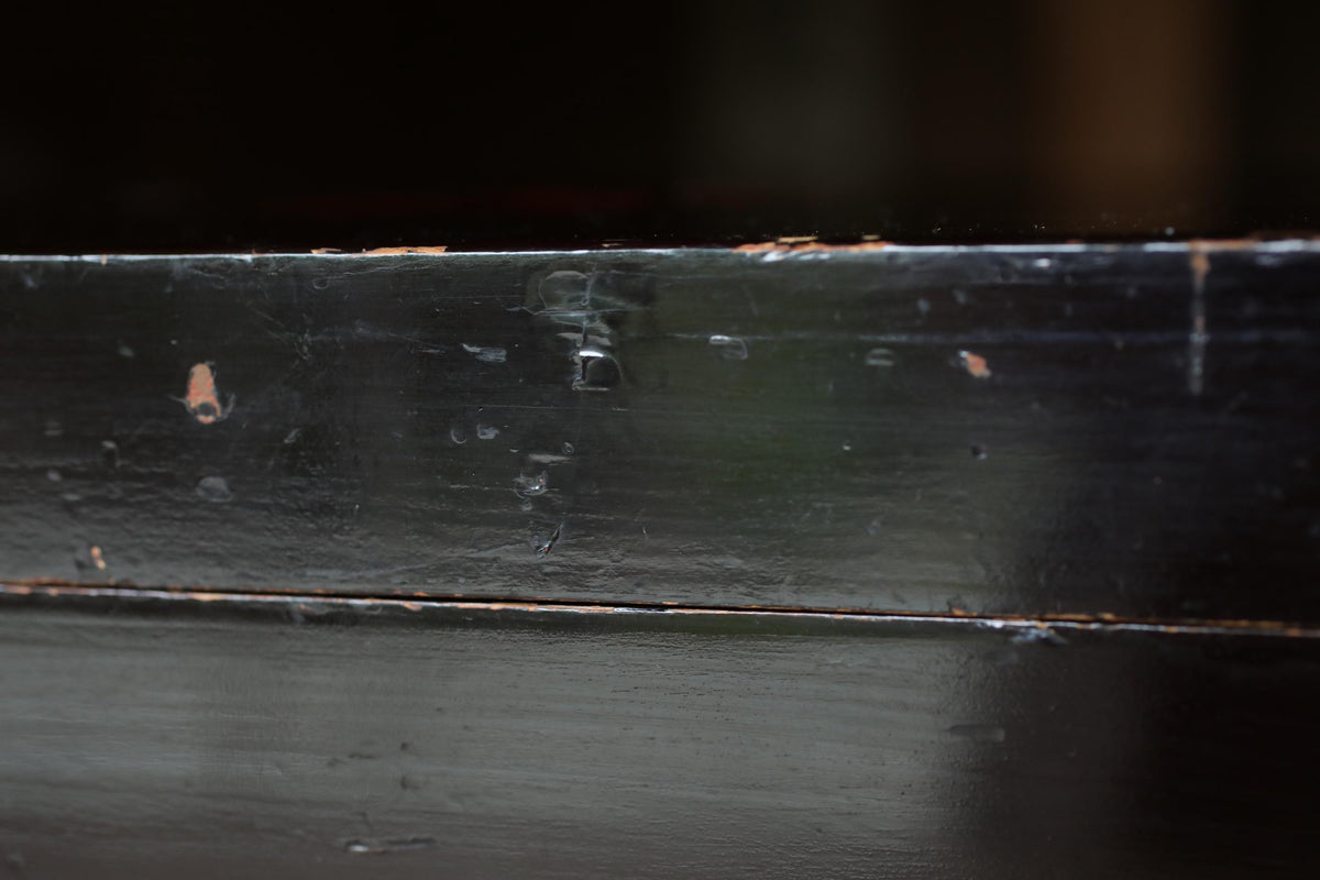a close-up view of a black, textured surface with visible scratches and marks, suggesting it has been used or exposed to various elements over time.
