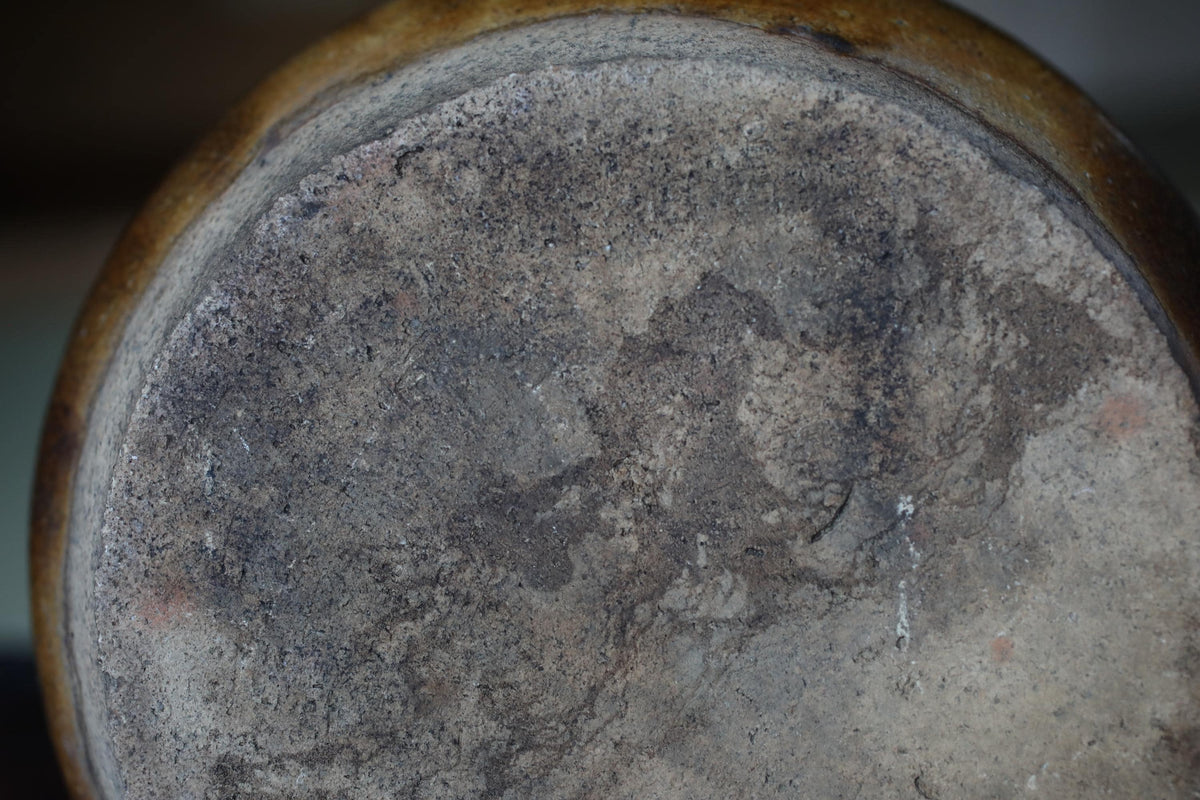 the bottom part of a ceramic or metal object, with a textured and worn surface.