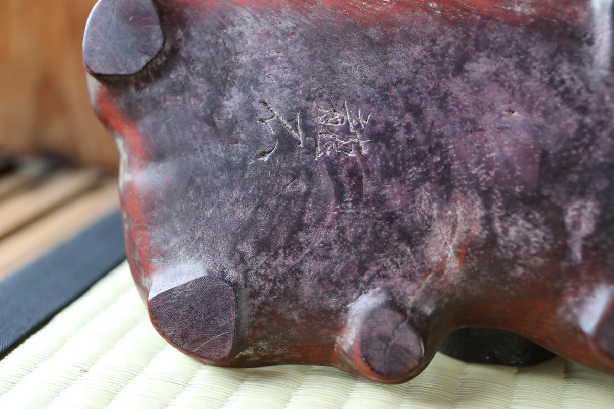 a close-up view of a dark red, possibly purple, ceramic object with a textured surface.