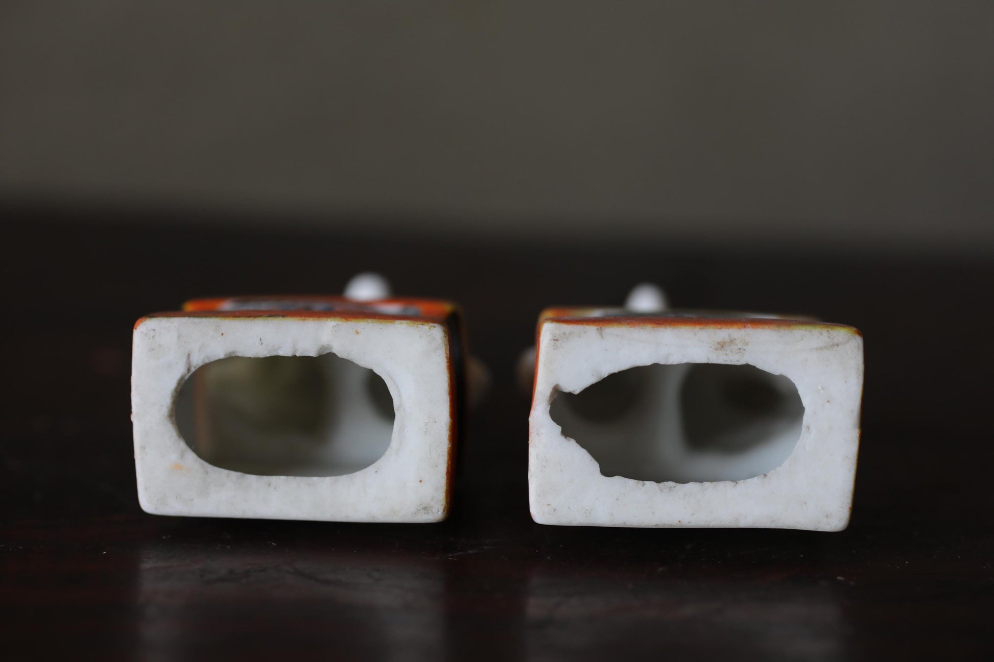 Two white ceramic objects with holes in the center, placed on a dark surface.