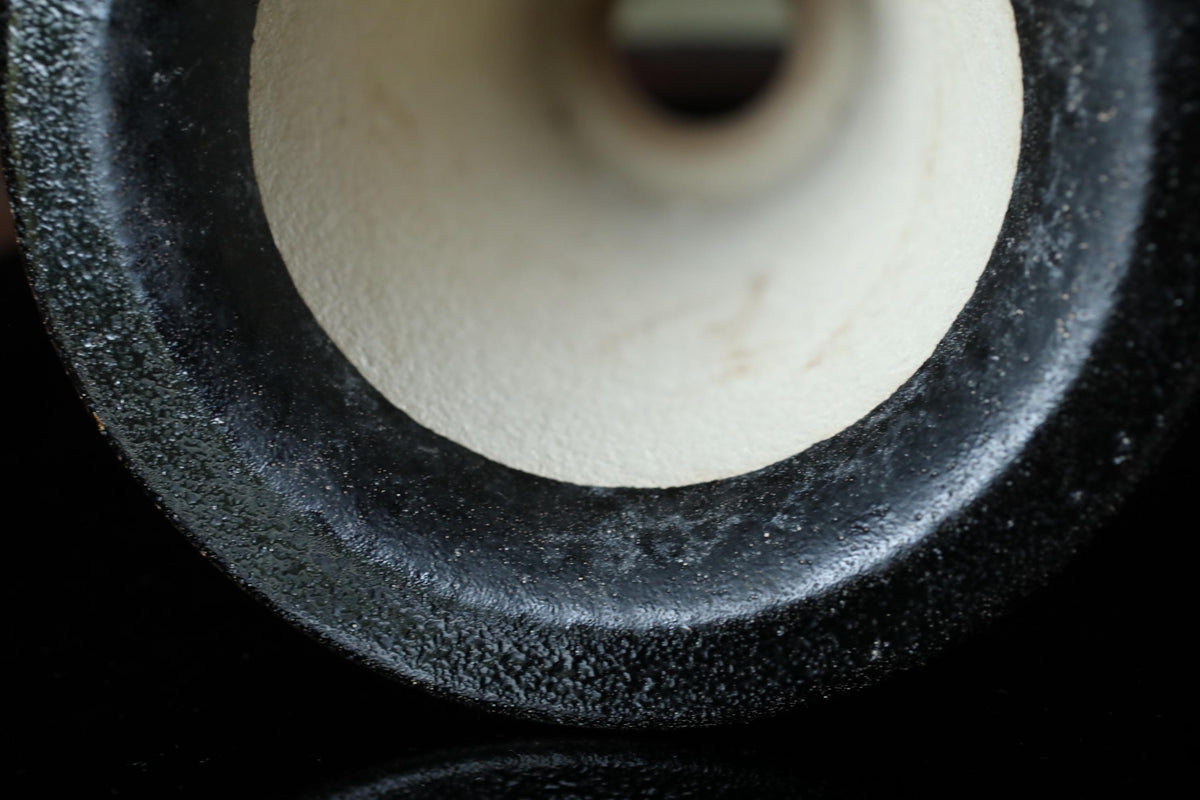A close-up view of a black and white object, possibly a piece of metal or a ceramic item, with a textured surface and a hole in the center.