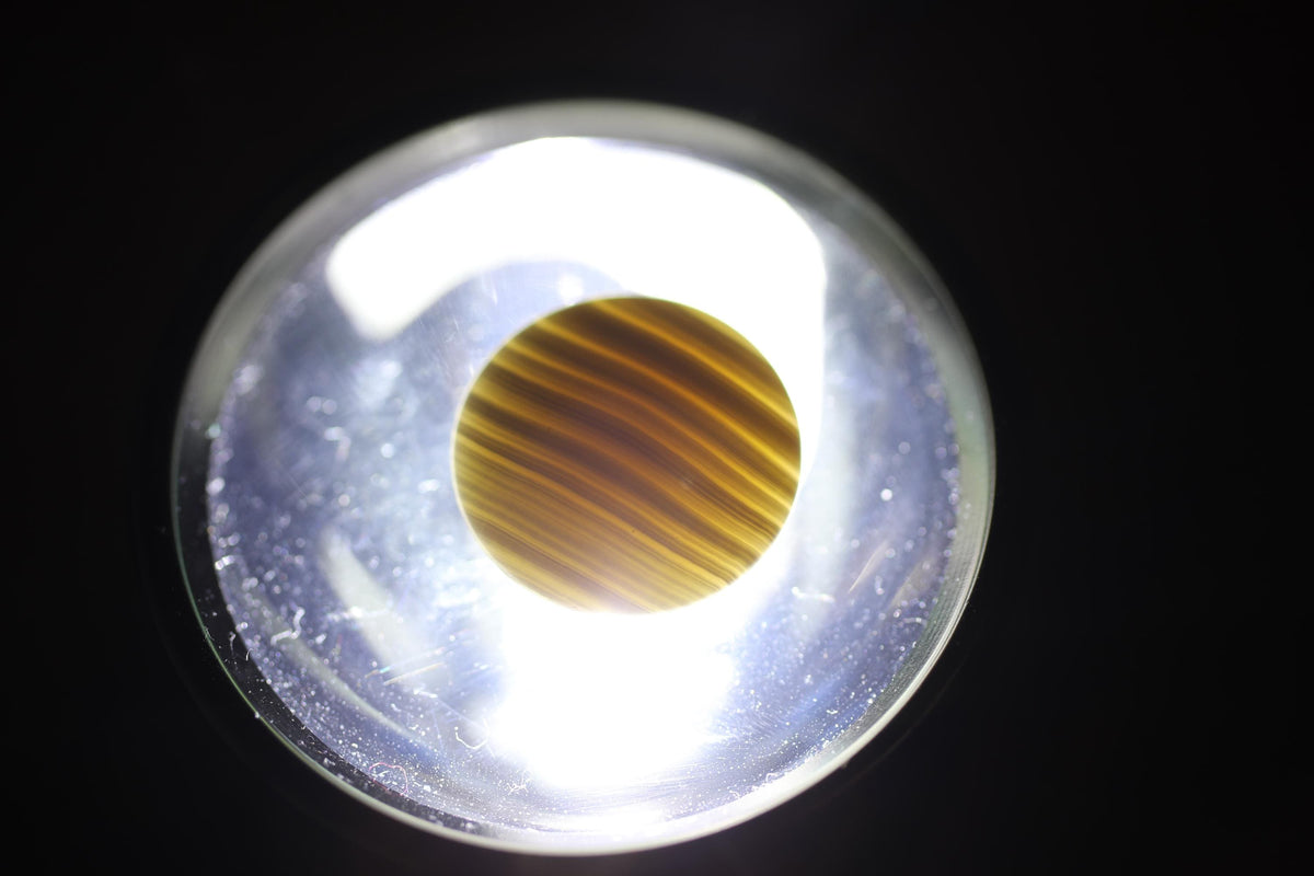 a close-up view of a yellow and black striped object, possibly a piece of fabric or paper, illuminated by a light source.