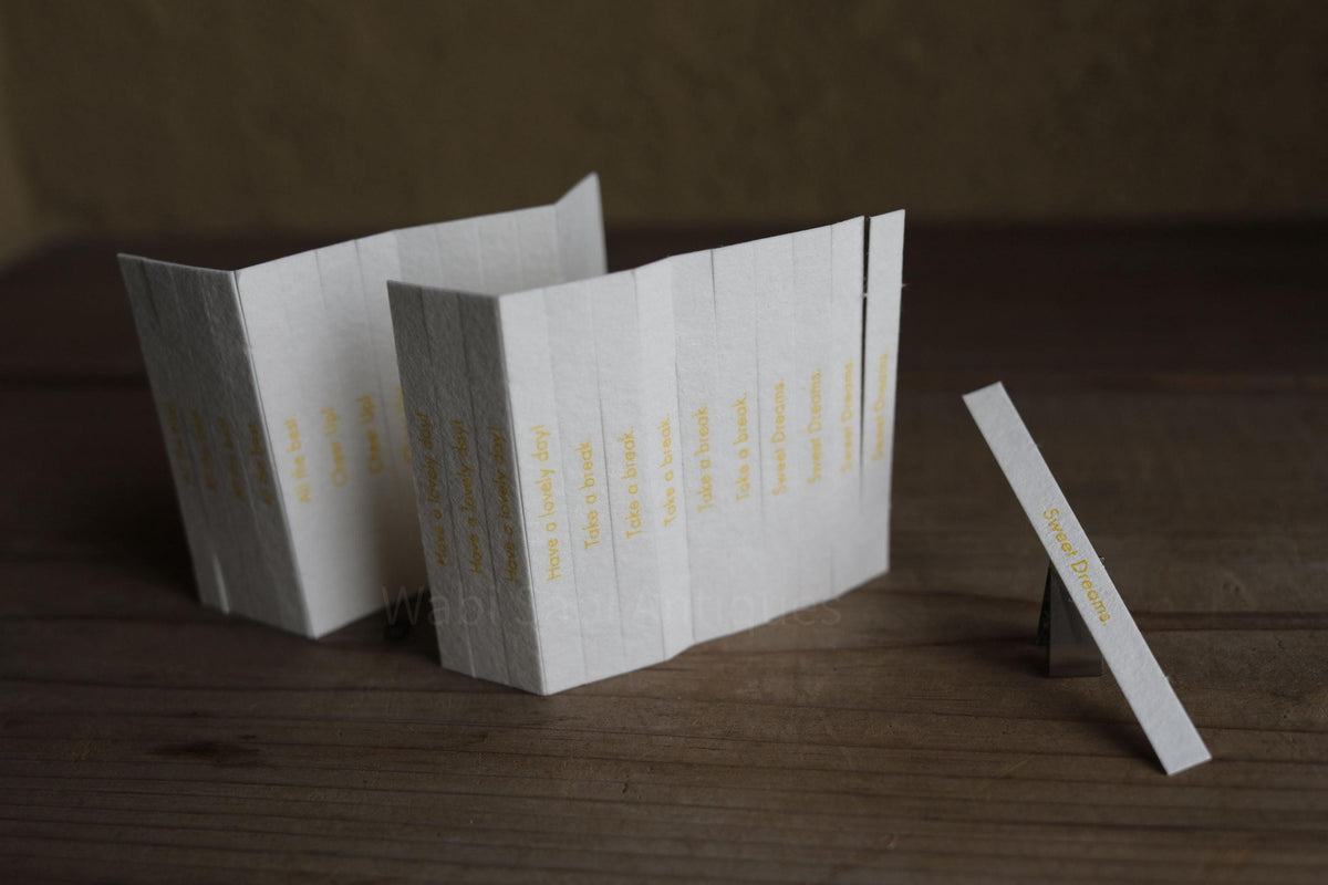 a collection of white paper strips arranged on a wooden surface, with the text "Sweet Dreams" visible on one of the strips.