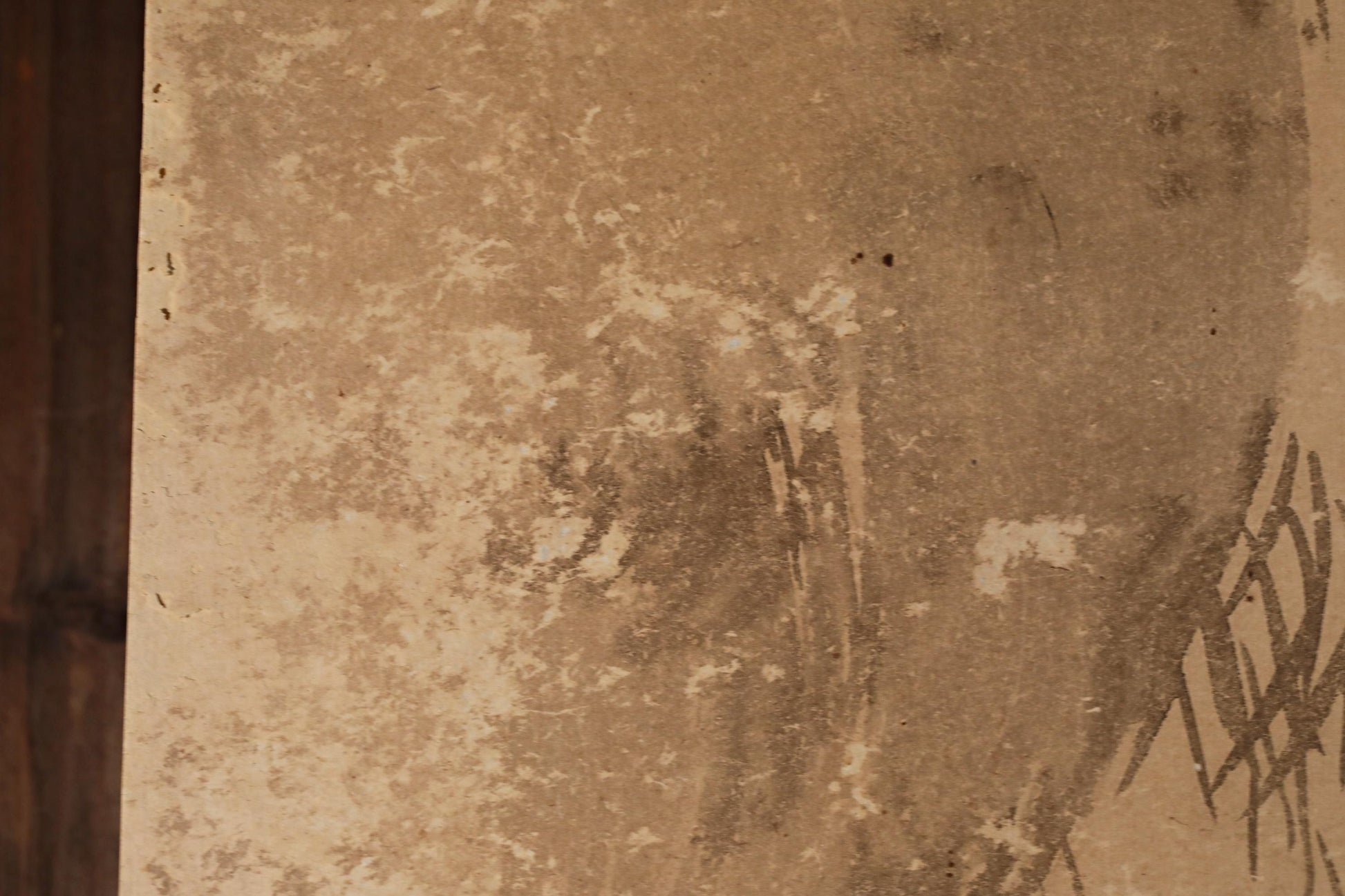 a close-up view of a textured surface, possibly a wall or a piece of paper, with some visible stains or marks.