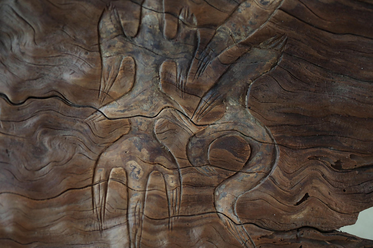 a close-up view of a wooden surface with intricate carved patterns, including a snake-like design.