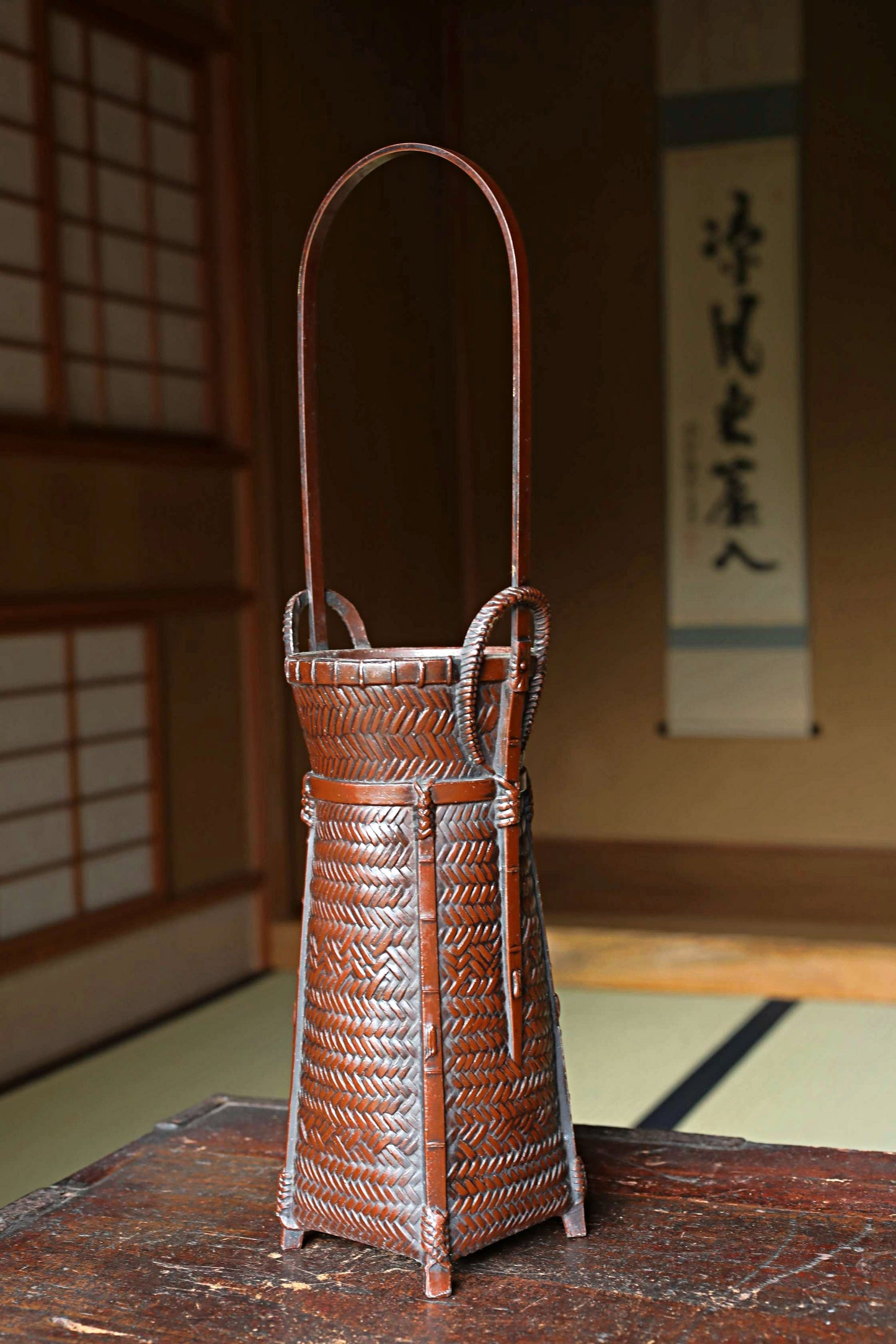A traditional Japanese woven basket with a curved handle, placed on a wooden surface.