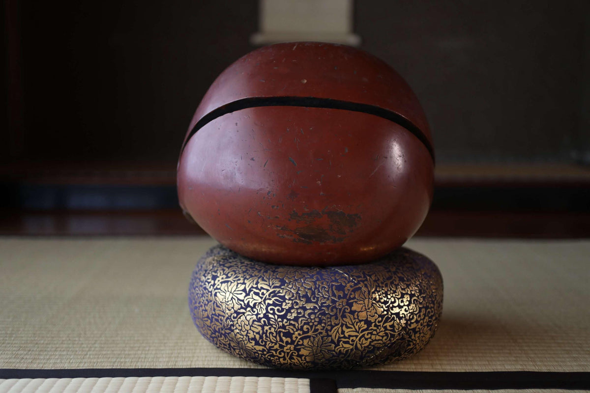 a red bowl with a black line running through it, placed on top of a blue and gold decorative object.