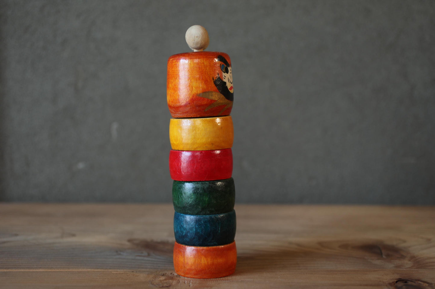 A stack of colorful wooden rings on a wooden surface.