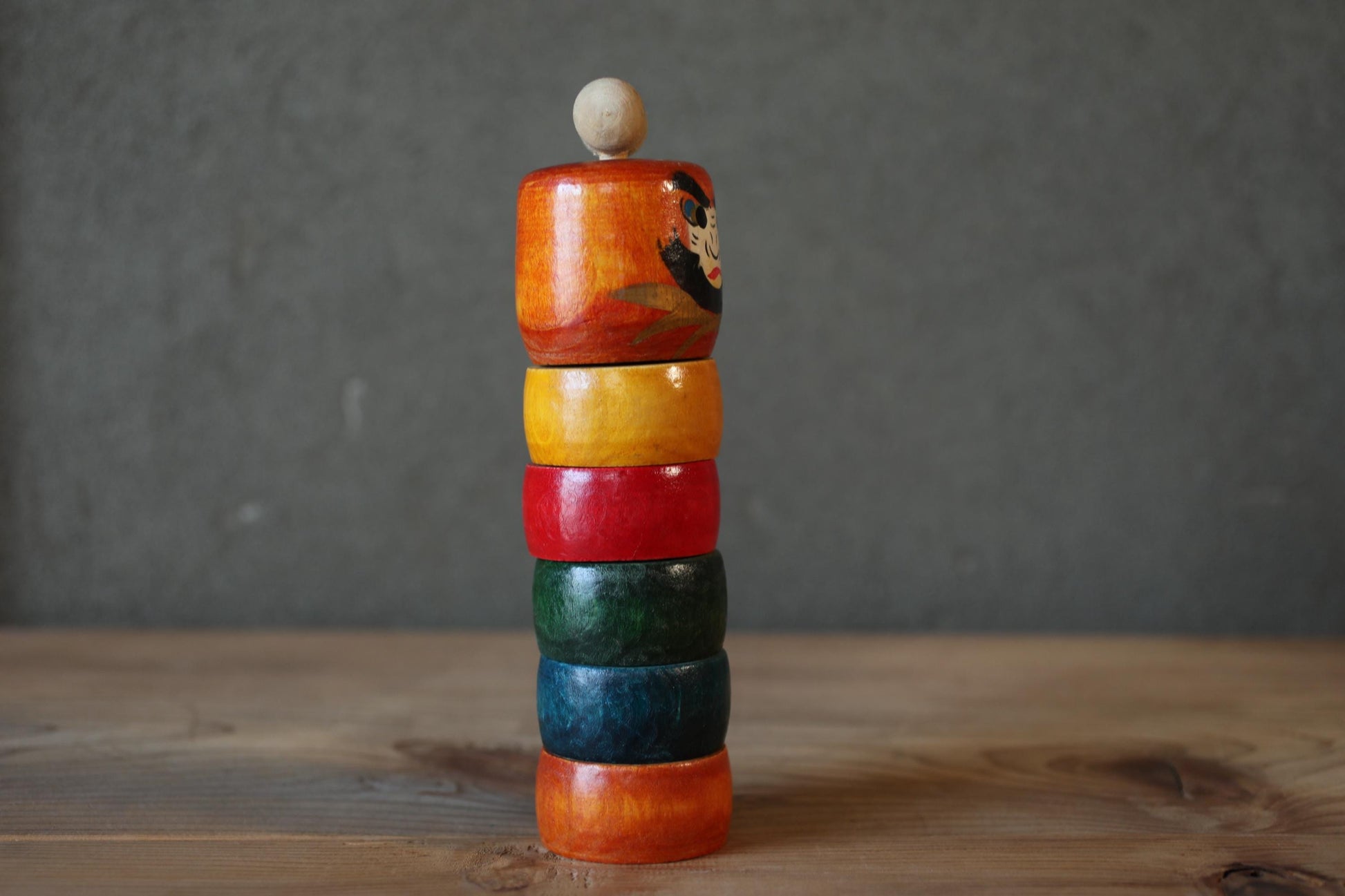 A stack of colorful wooden rings on a wooden surface.