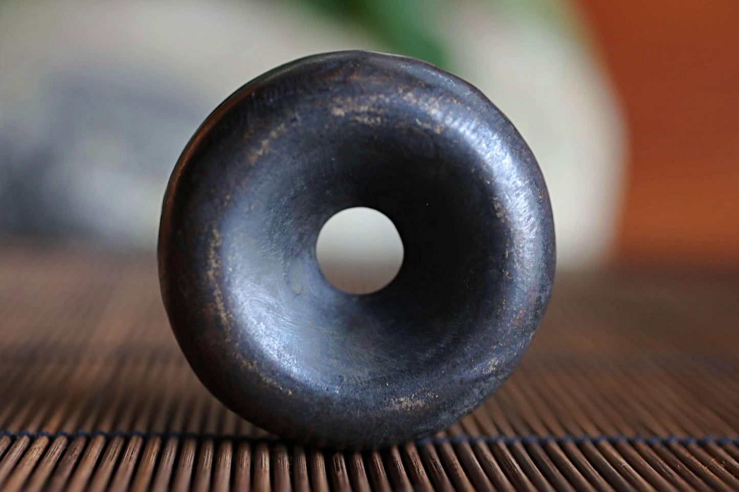 A close-up image of a black, circular object with a hole in the center, resting on a wooden surface.