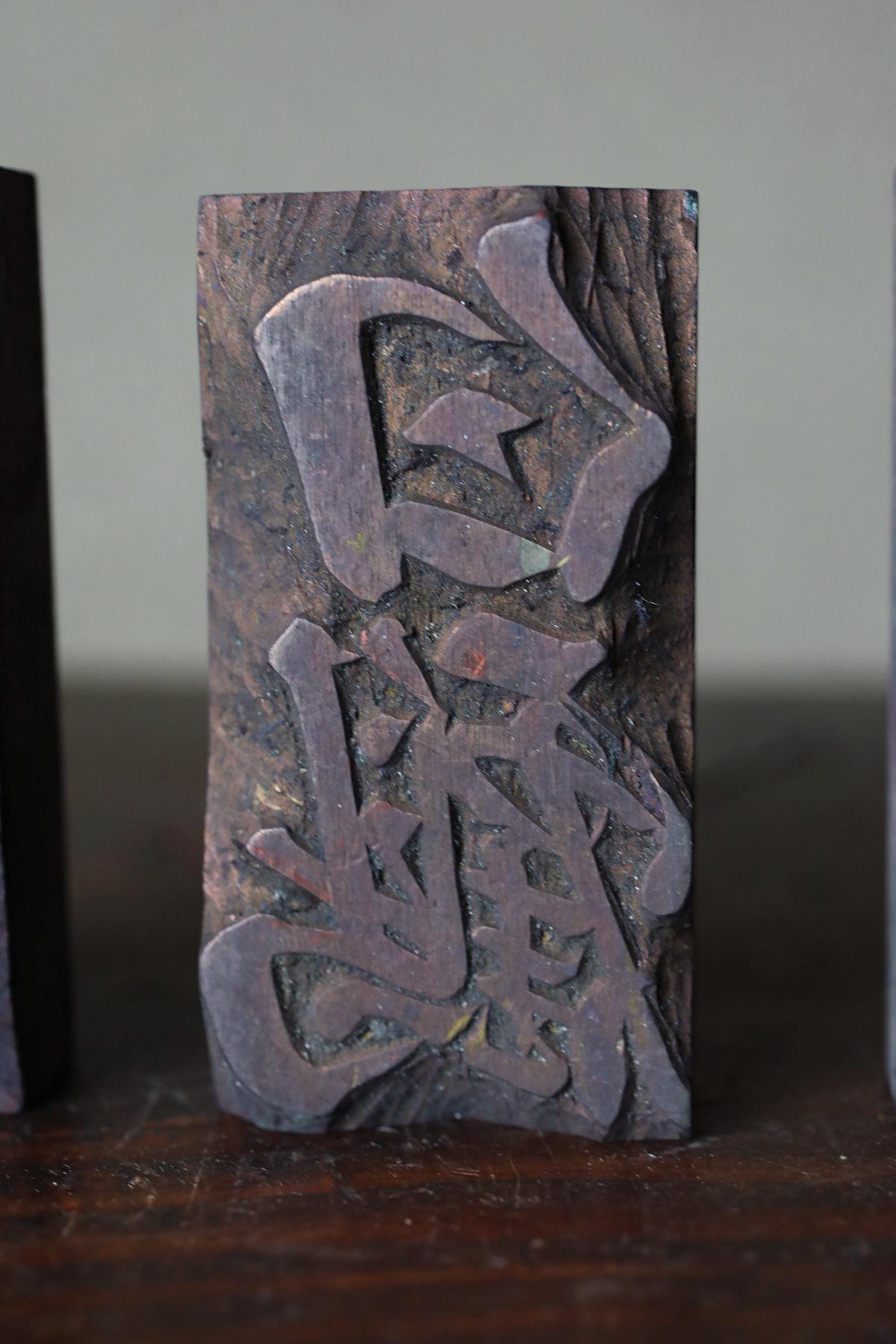 a dark wooden block with an intricate carved design, including a symbol or text that is not fully visible.