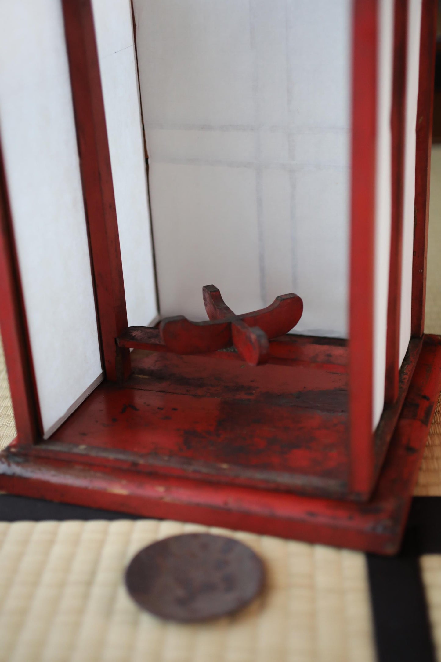 a red wooden lantern with a white interior, placed on a black and white mat.
