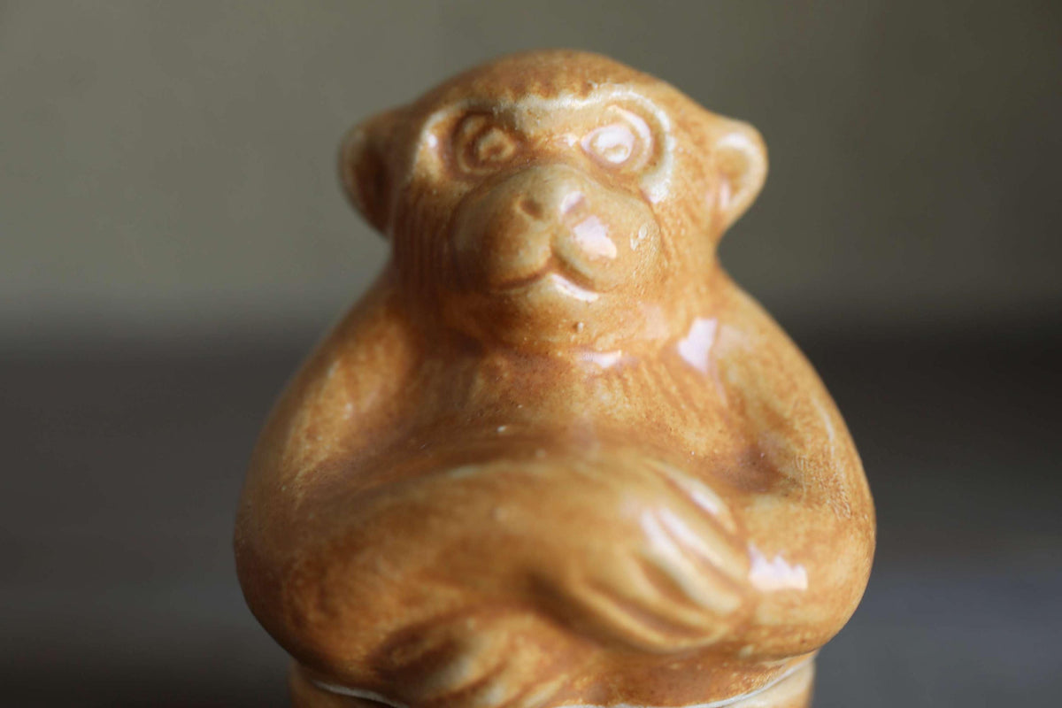 A ceramic monkey figurine is sitting on a surface.