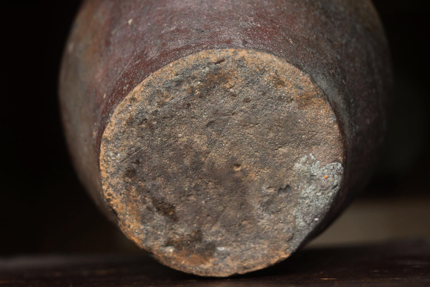 the bottom part of a rusted, old vase or container with a weathered, worn appearance.