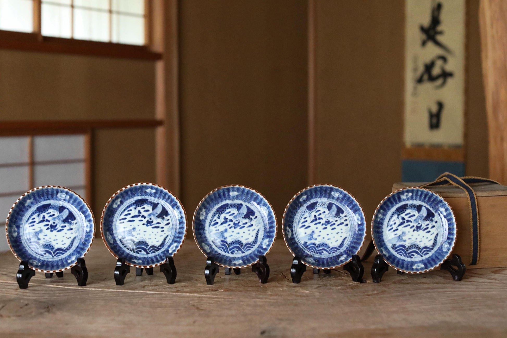 A row of five blue and white plates with intricate designs, displayed on a wooden surface.