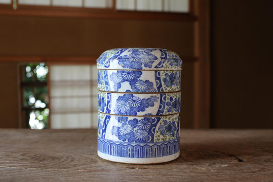 A blue and white ceramic container with a floral pattern sits on a wooden surface.