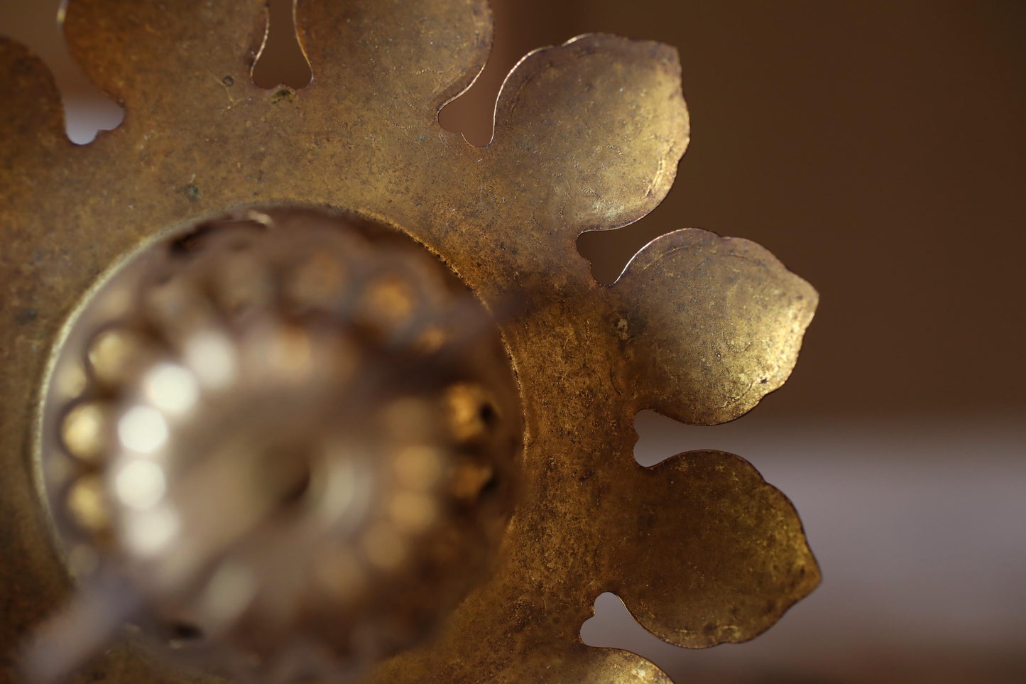 a close-up view of a rusted metal object with a flower-like shape, possibly a piece of jewelry or a decorative item.