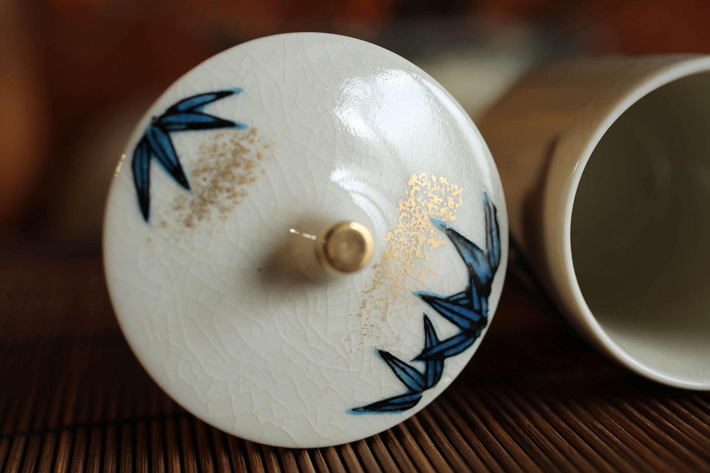 A close-up image of a white ceramic lid with blue floral designs, placed on a wooden surface.