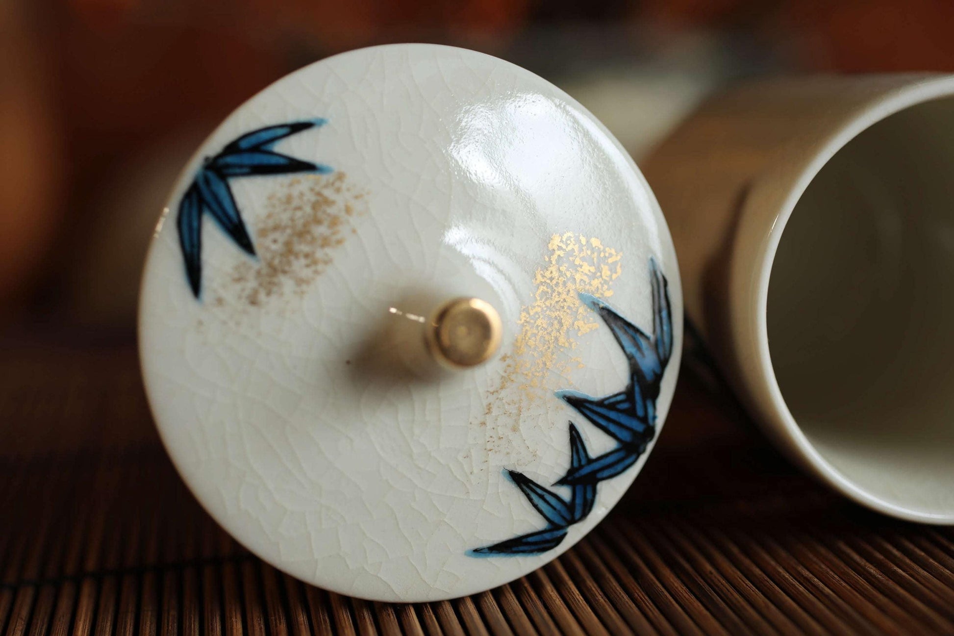 A close-up image of a white ceramic lid with blue floral designs, placed on a wooden surface.