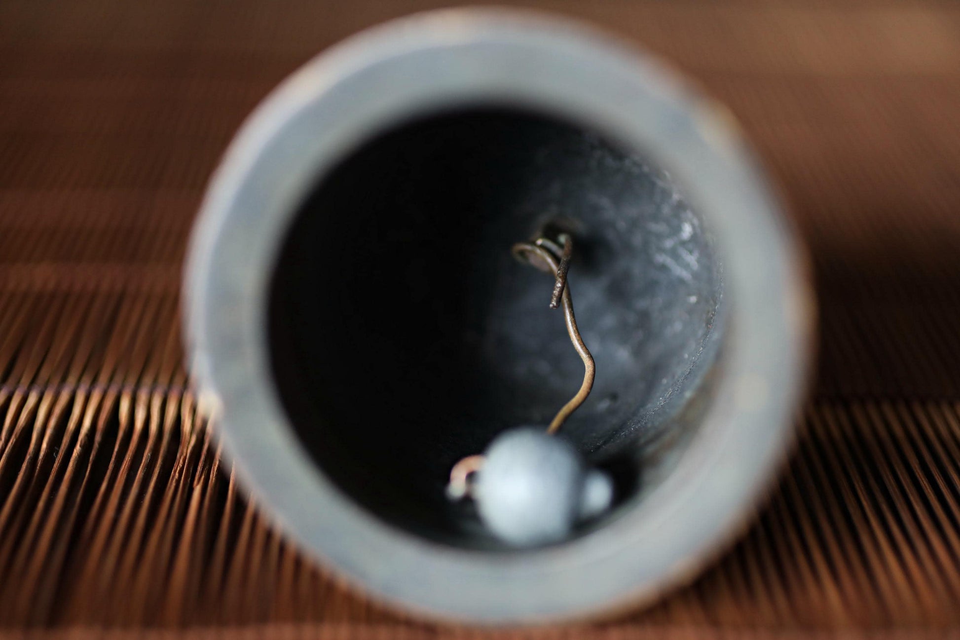 a close-up view of a bell, with a small white ball inside the bell and a string or cord extending from the bell.