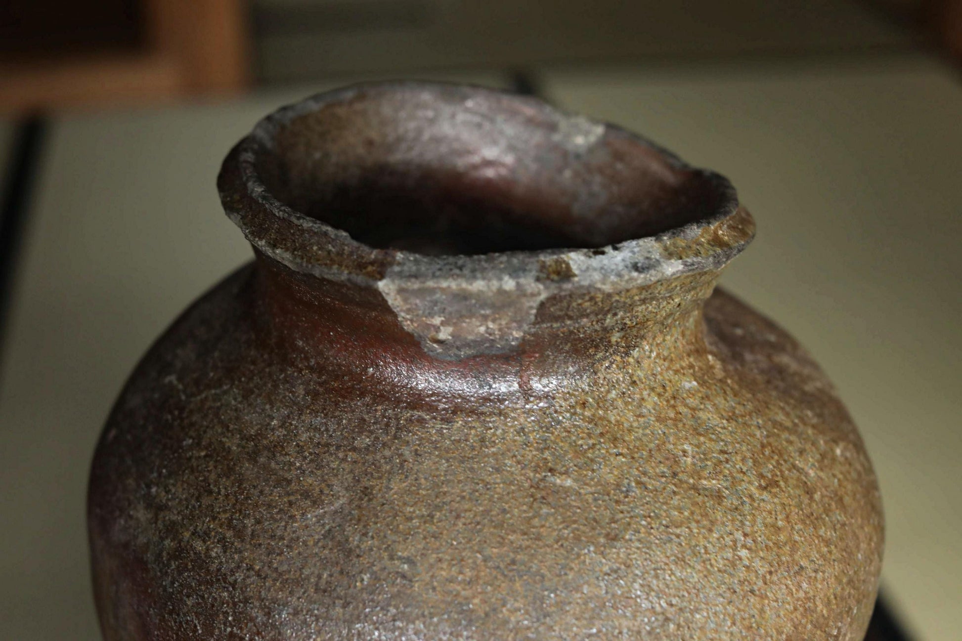 A close-up image of a weathered, brown ceramic vase with visible cracks and chips.