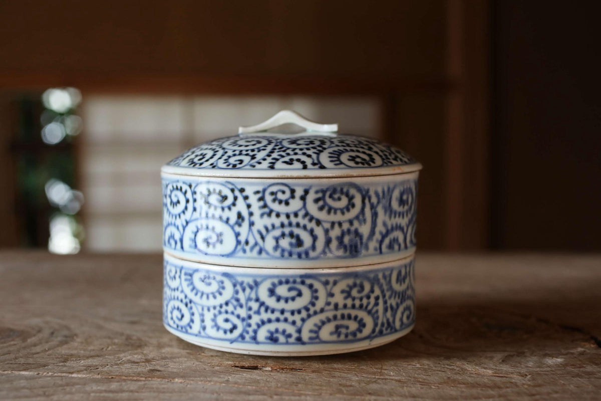 A decorative blue and white ceramic container with a lid sits on a wooden surface.