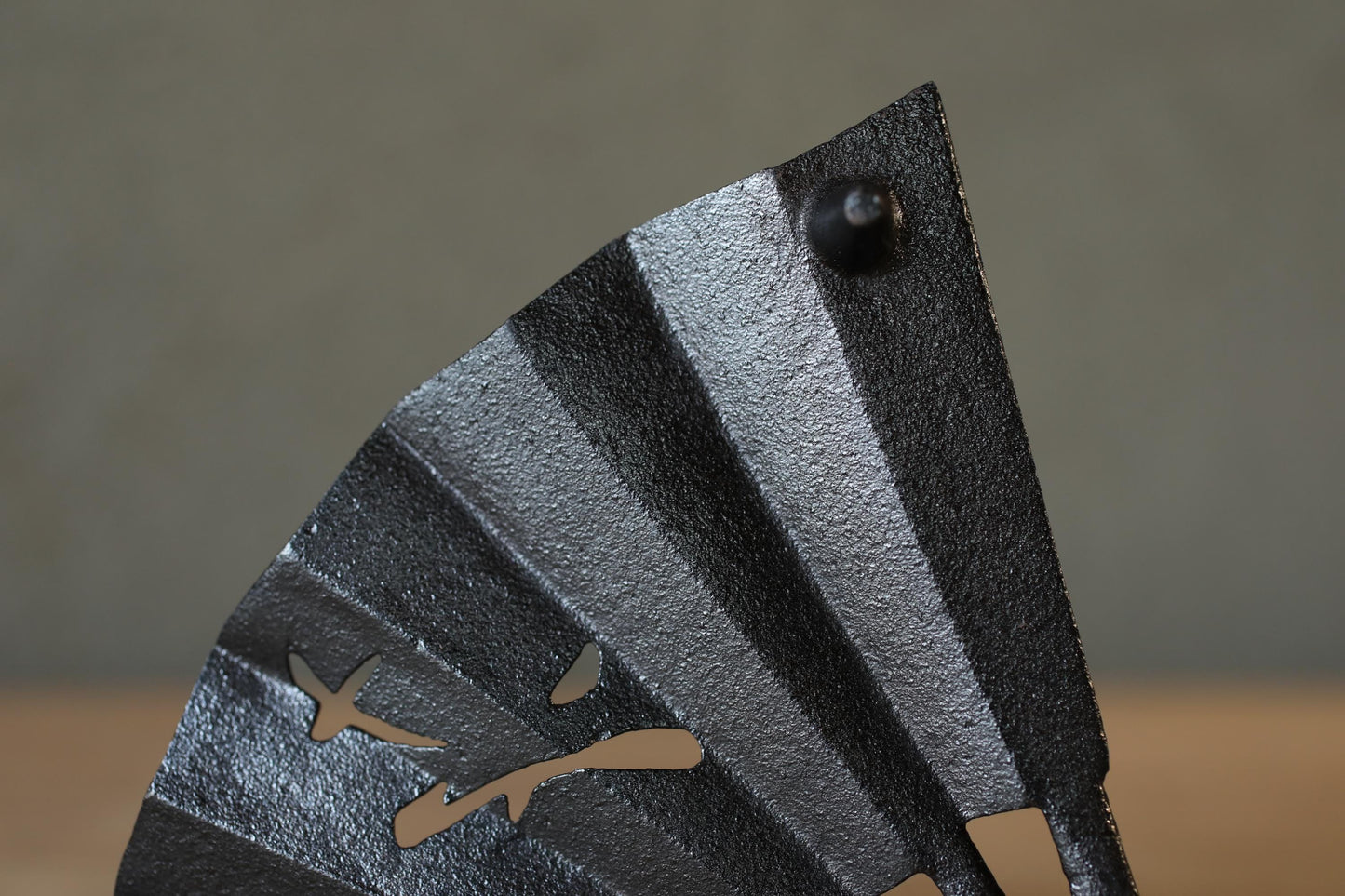 A close-up view of a black metal fan blade with a decorative design.
