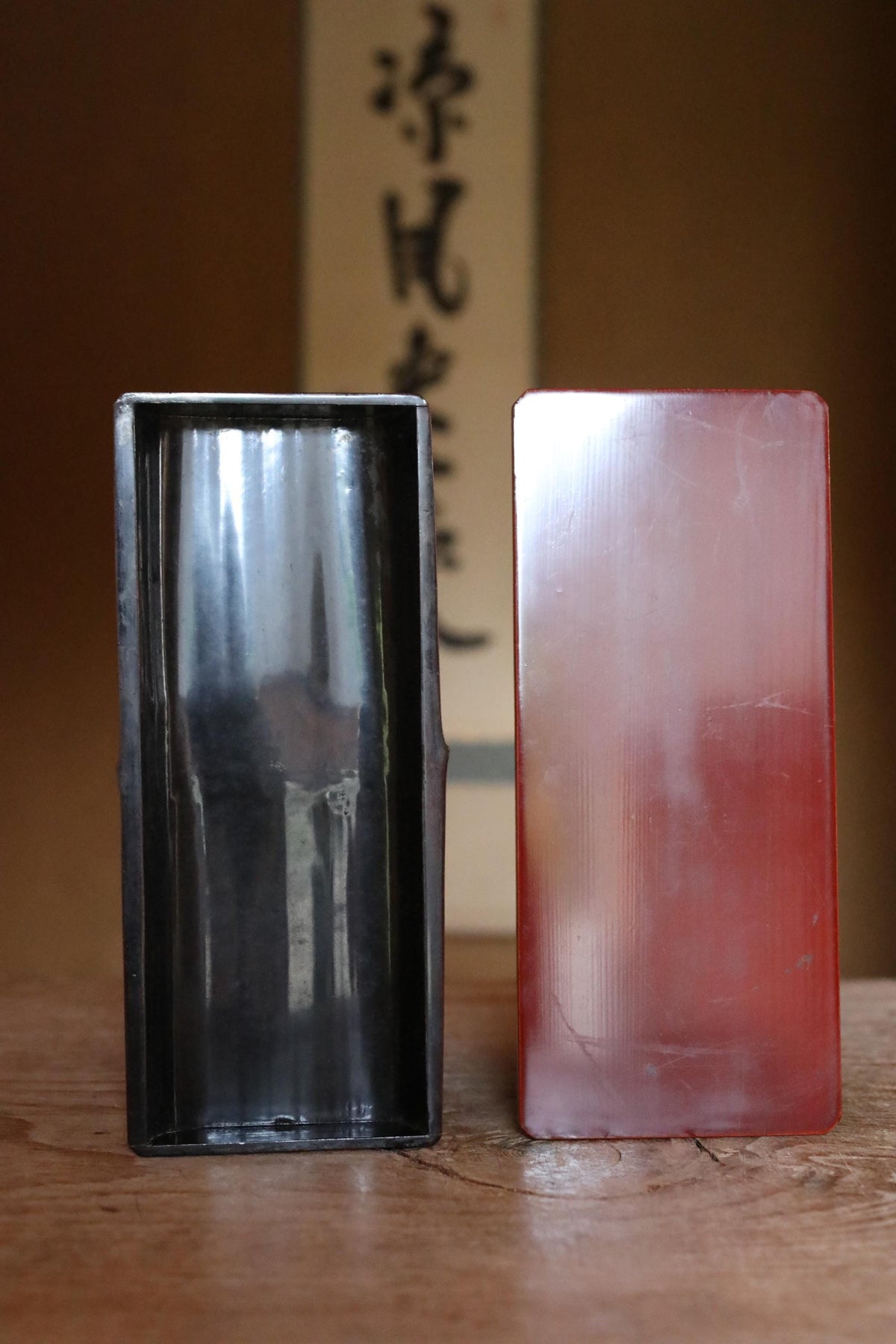 two rectangular objects, one black and one red, placed on a wooden surface.