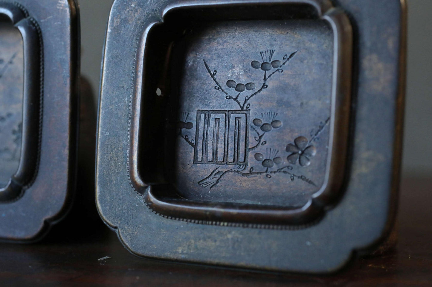 a close-up view of a dark metal object, possibly a piece of art or a decorative item, with a floral design on it.